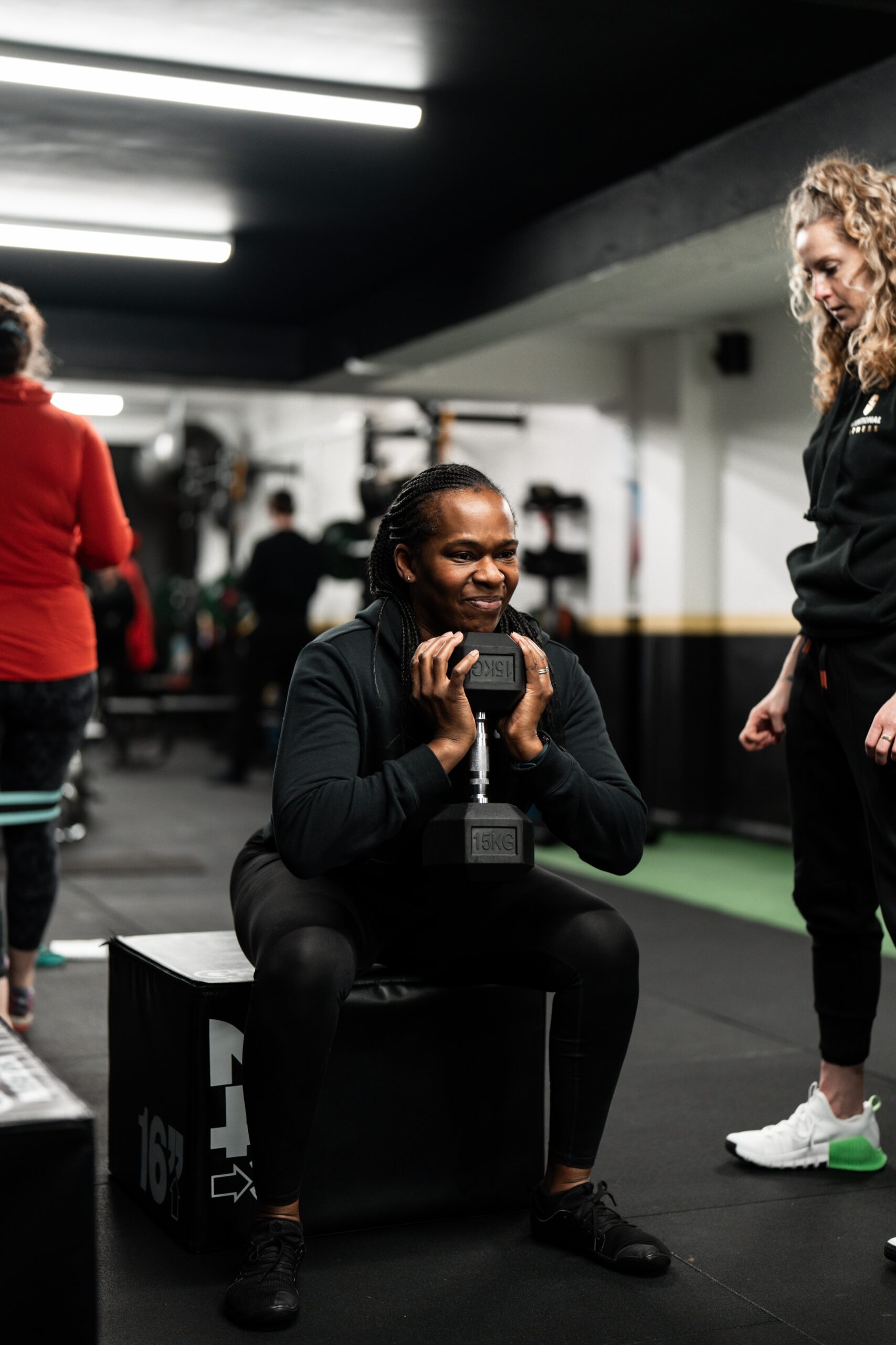 Intentional Fitness member being supported by a coach while squatting at a Small Group Personal Training session.